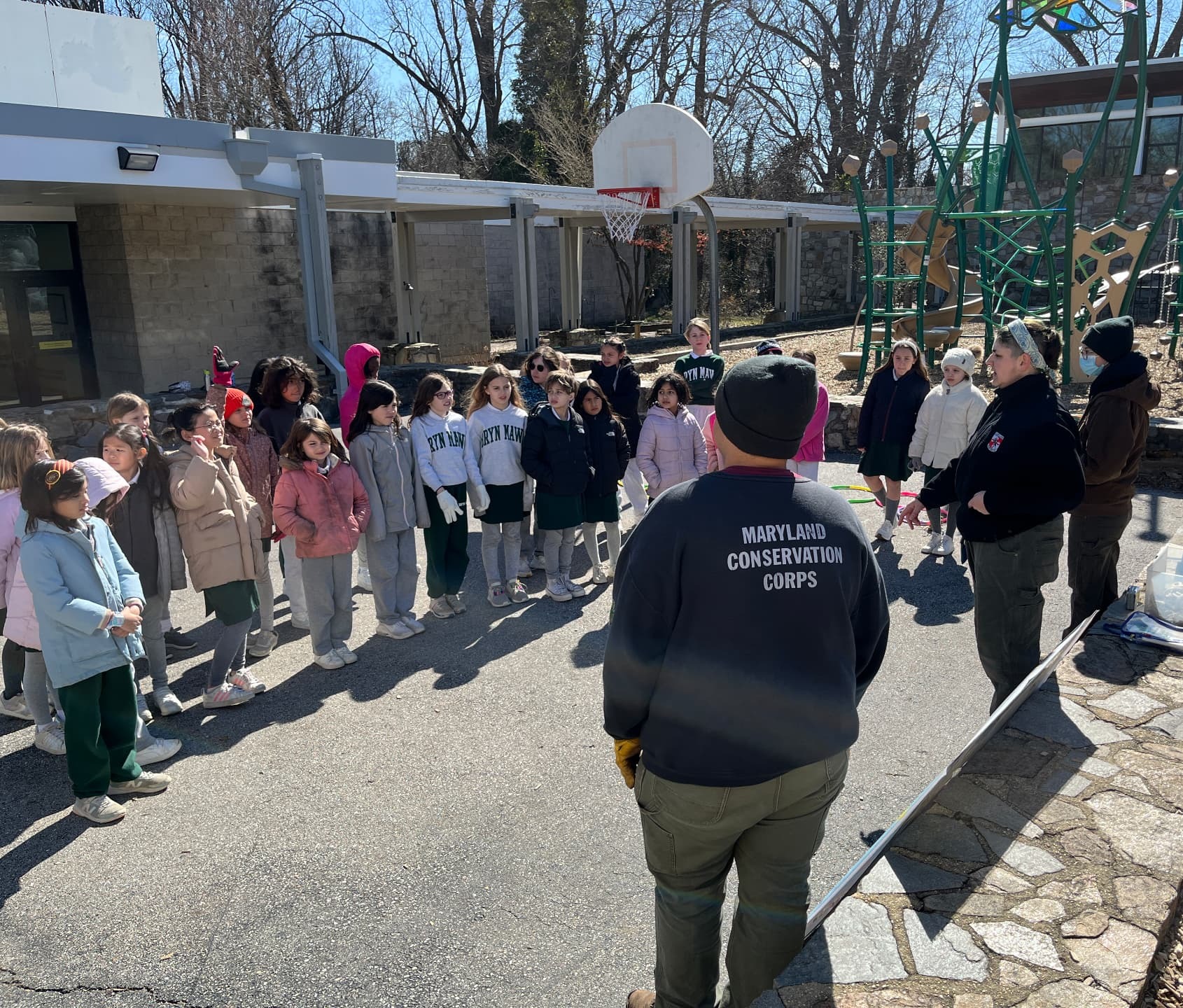 Maryland Conservation Corps members speak with Bryn Mawr School students on the playground about protecting ospreys and hawks